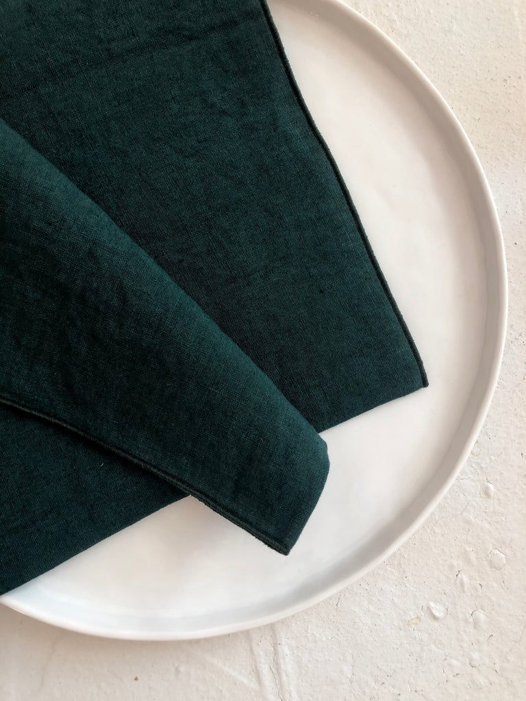 teal green rolled edge linen napkins 18 inch square folded on plate