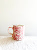 cream mug with pink splatter pattern on white table