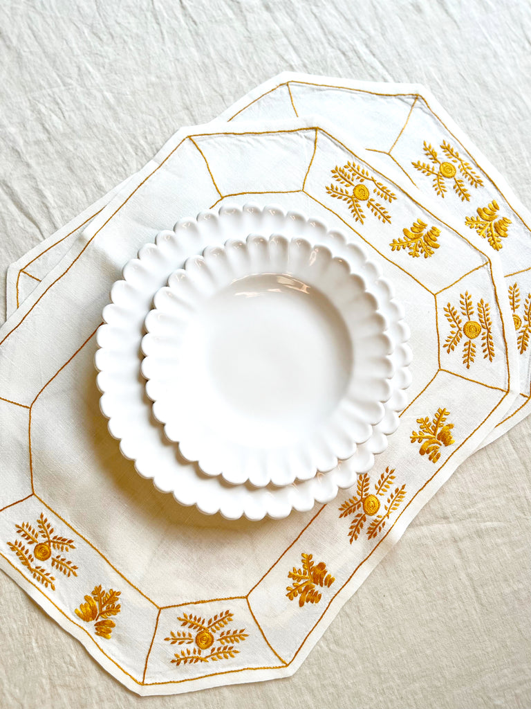 octagonal white linen placemat with gold embroidery 19.5" by 16" on table