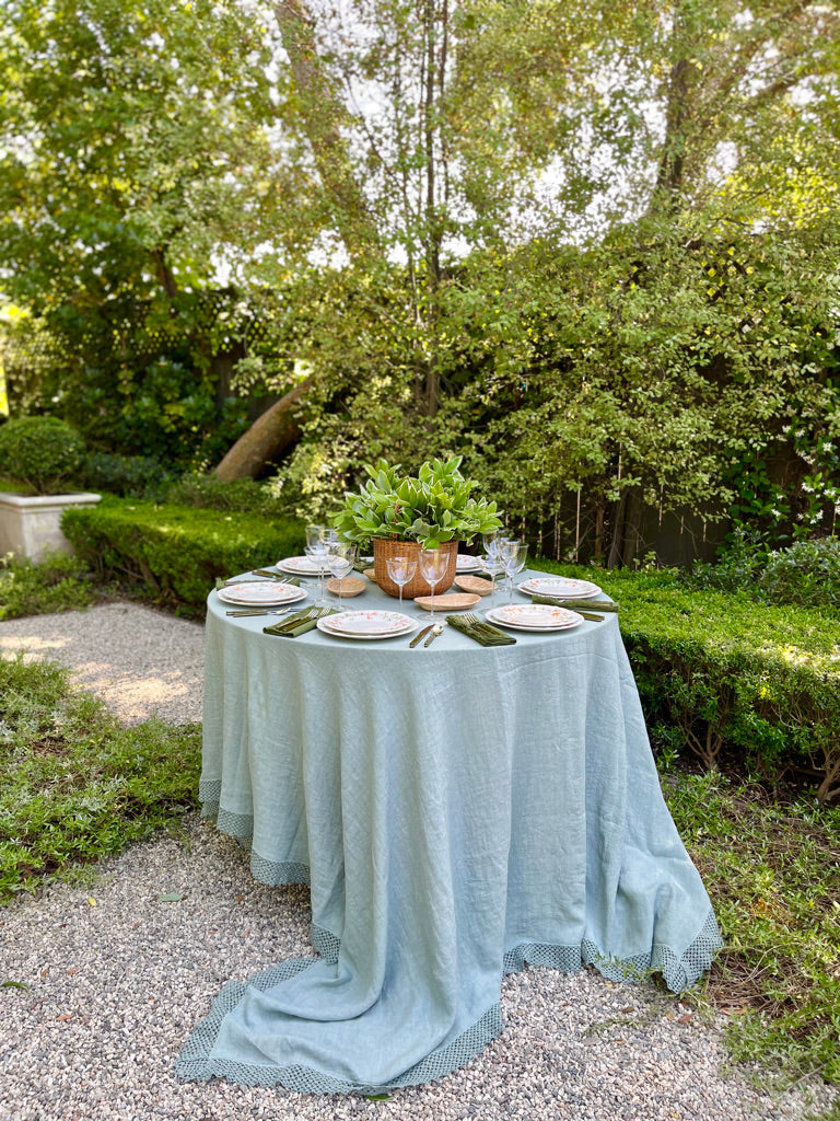 sage green linen tablecloth with macrame trim on round table