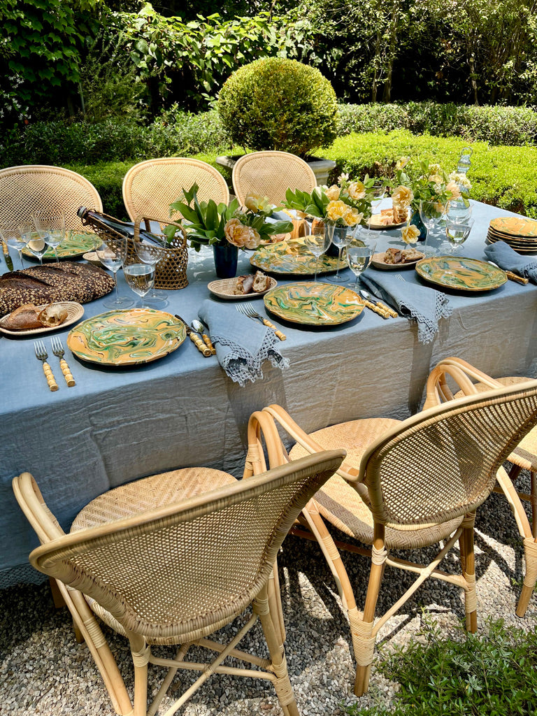 Blue Milano Macrame Tablecloth 74 inch shown outside on a table with rattan chairs