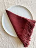 burgandy linen napkins with fringe on white plate