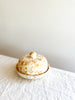 round white covered dish with tan speckled pattern on white table