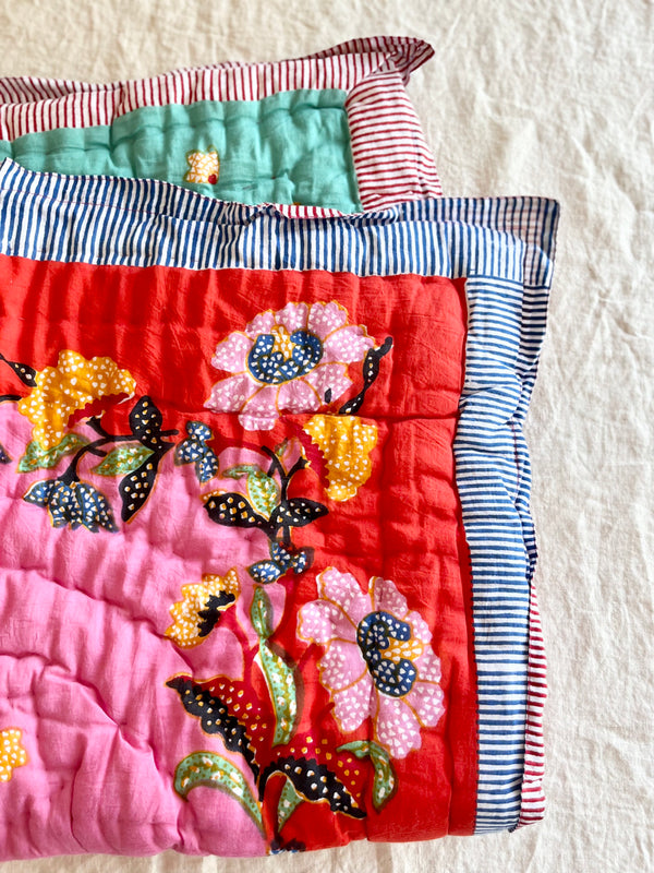 red and pink cotton quilt with pink and yellow flowers and a blue and white striped border 27 x 40 inches detail view