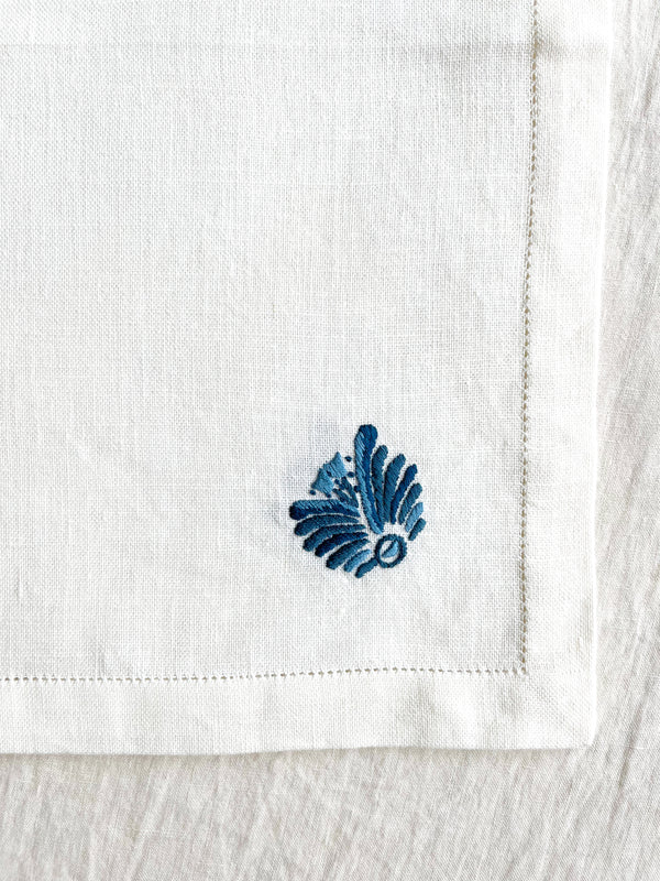 white hand embroidered linen napkins with blue palm frond in corner 16 inches square detail view