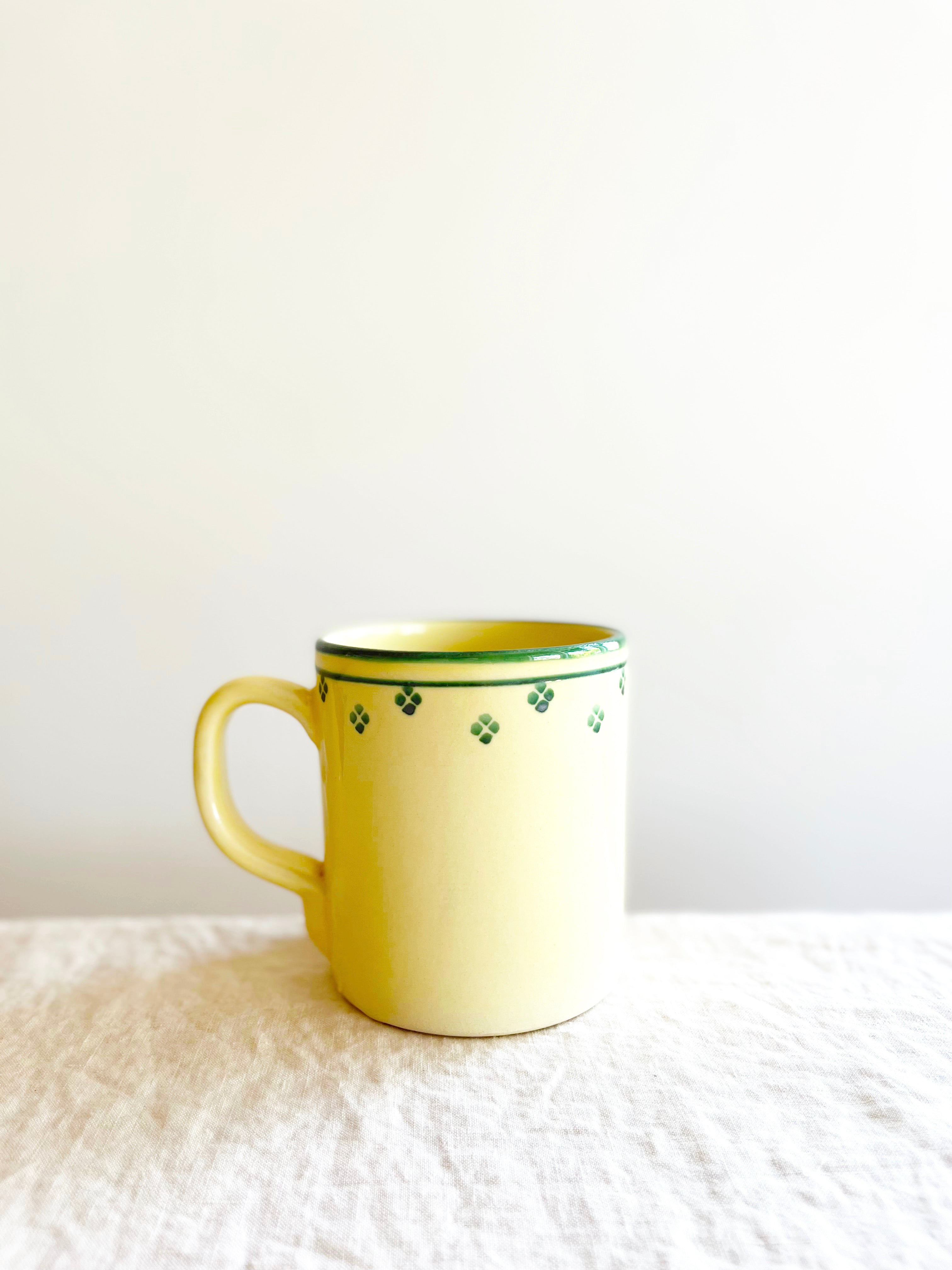 cream mug with green rim and dots around edge on table