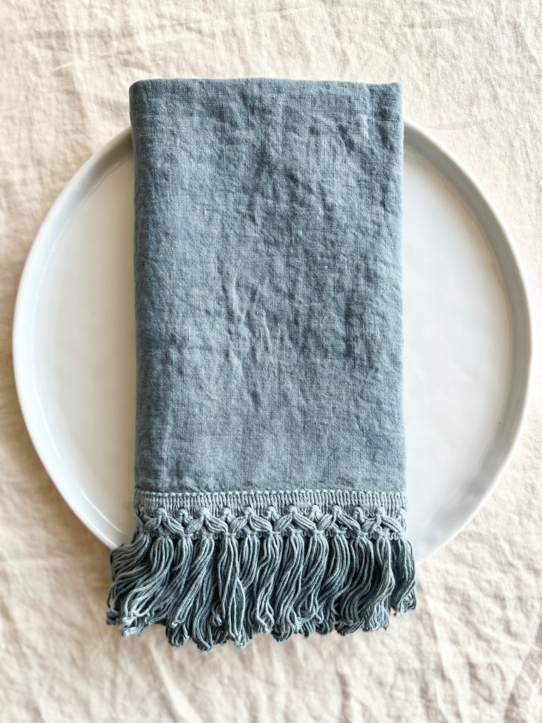 dusty blue linen napkins with fringed edge 18 inches square folded on plate