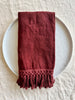burgandy linen napkins with fringe folded on table