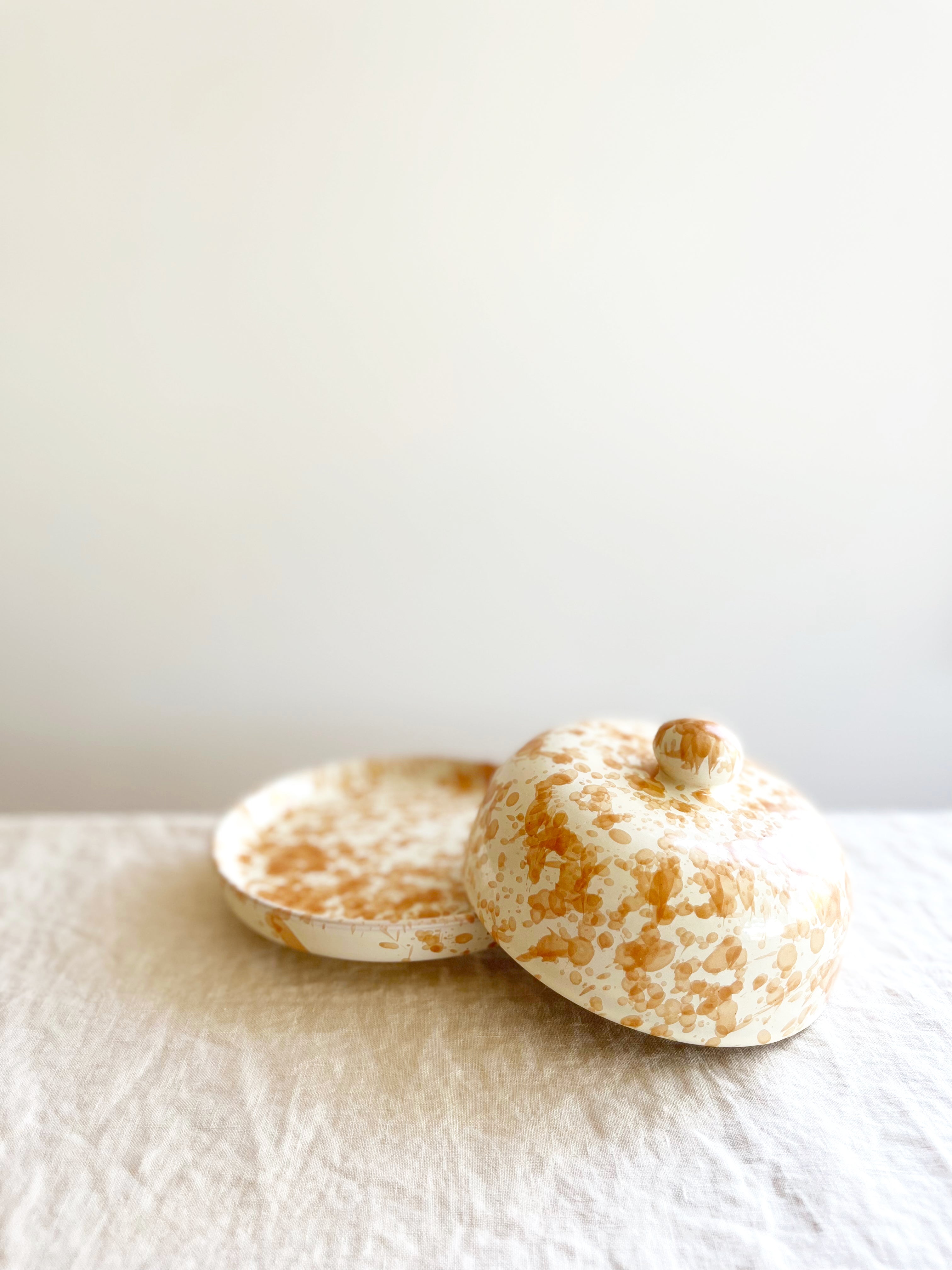 round white covered dish with tan speckled pattern with lid off