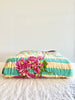 green striped cotton quilt with bougainvillea in center folded on table