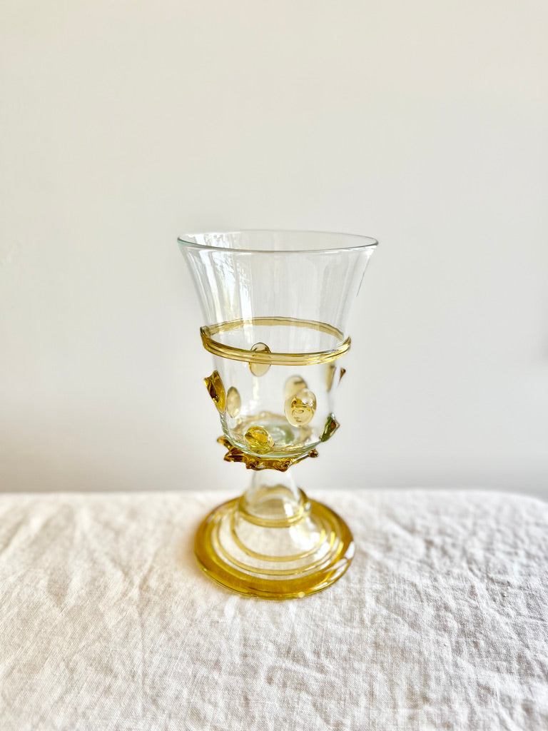 hand blown glass goblet with amber accents on white linen tablecloth