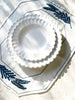 Octagonal dark blue embroidered white linen placemats shown with plates on top