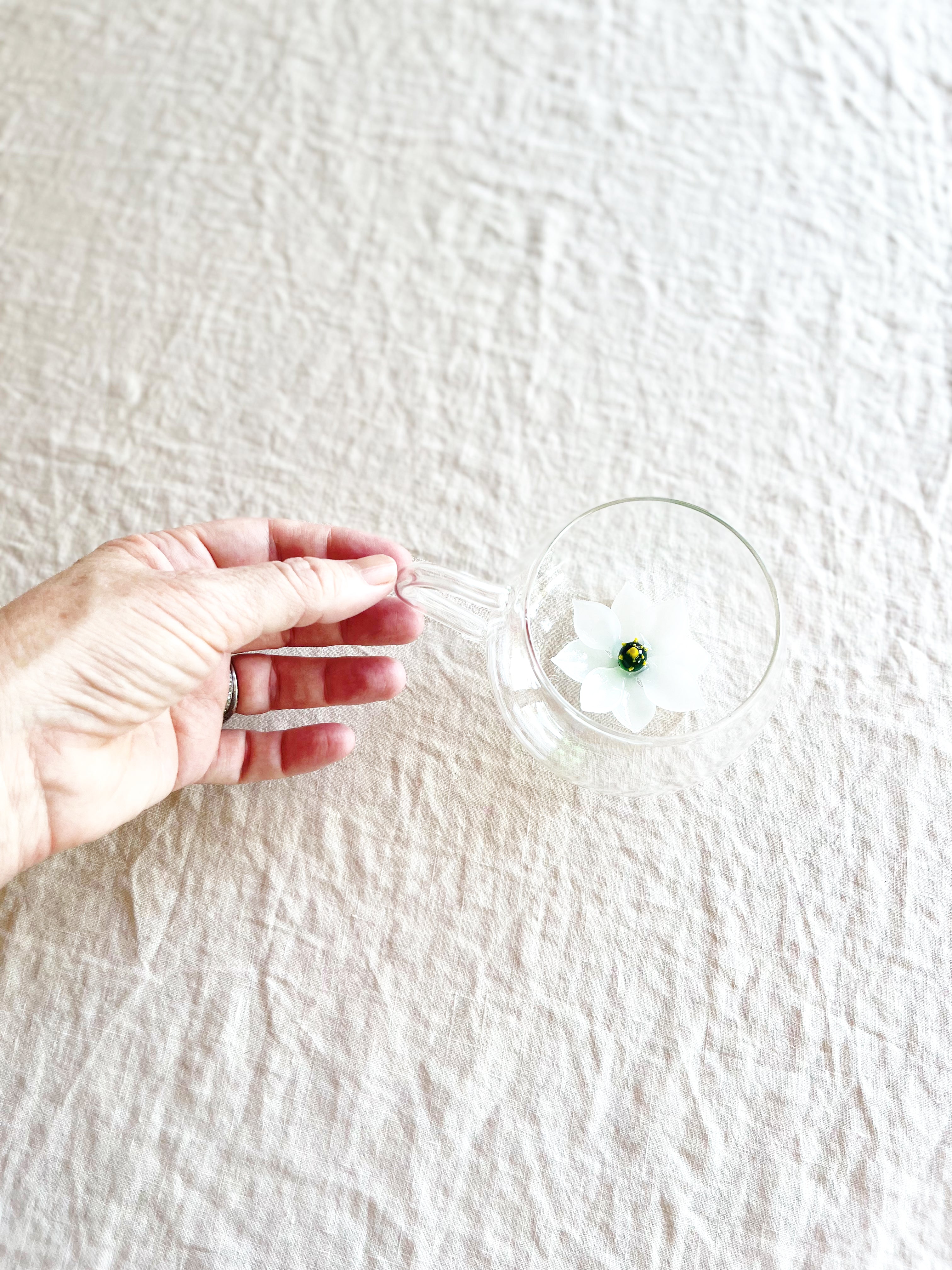 clear hand blown glass tea cup with white glass lotus flower in bottom top view