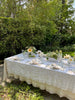 cream linen tablecloth with macrame trim on outdoor table