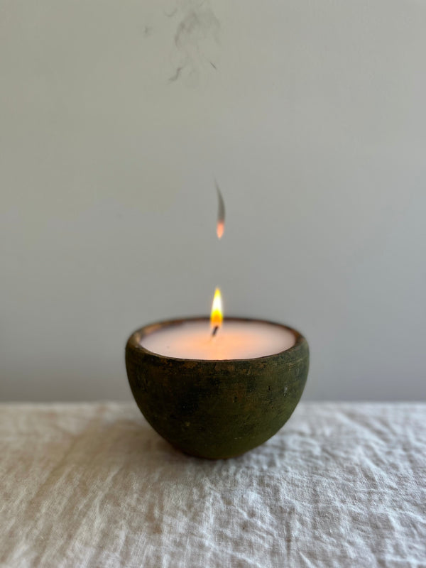candle in moss covered terra cotta pot with flame