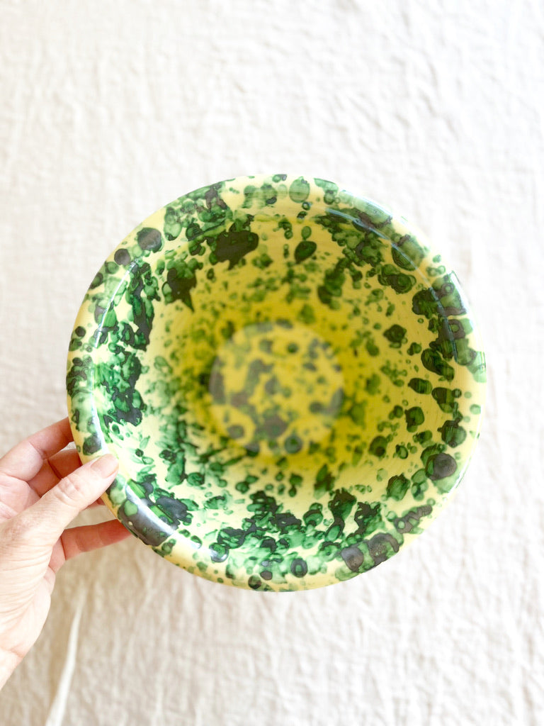 mixing bowls with splatter pattern in green and yellow color top view with hand