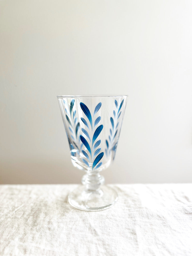 hand painted wine glasses with blue leaf pattern on white table