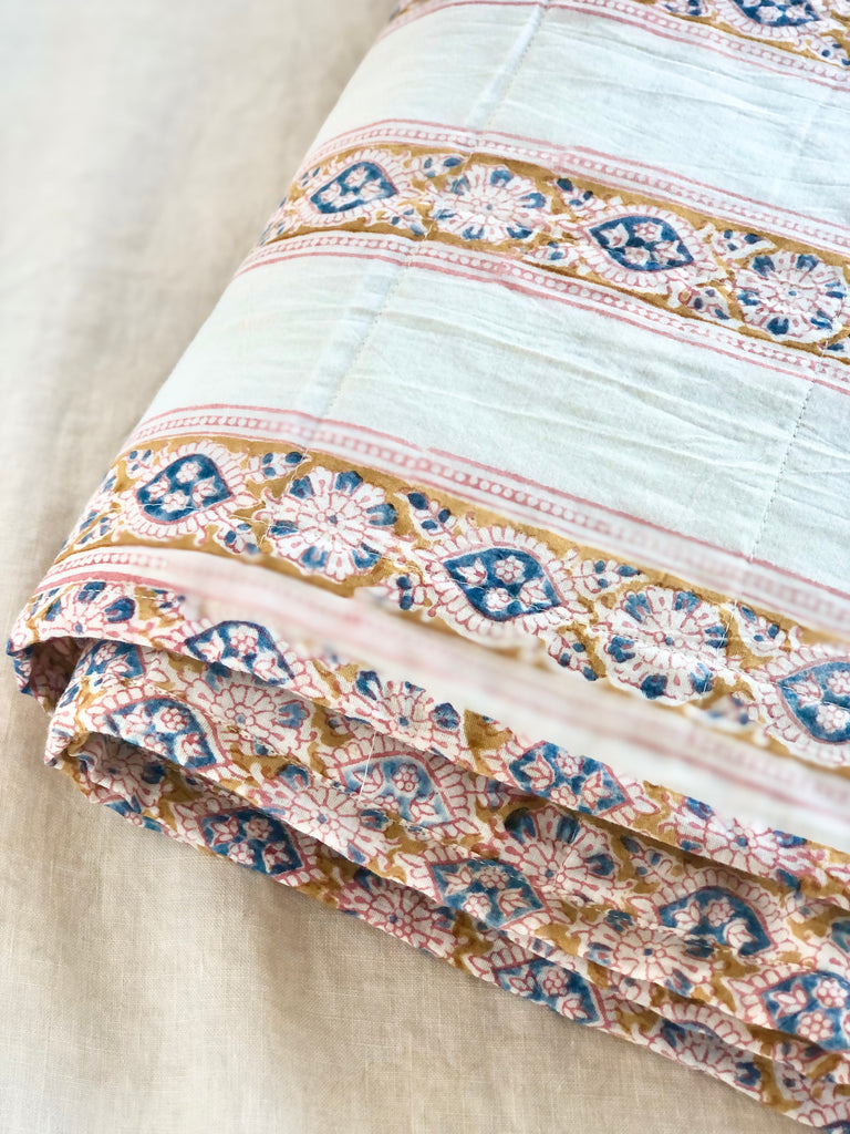 twin size white cotton quilt with gold, blue and pink floral stripes detail view