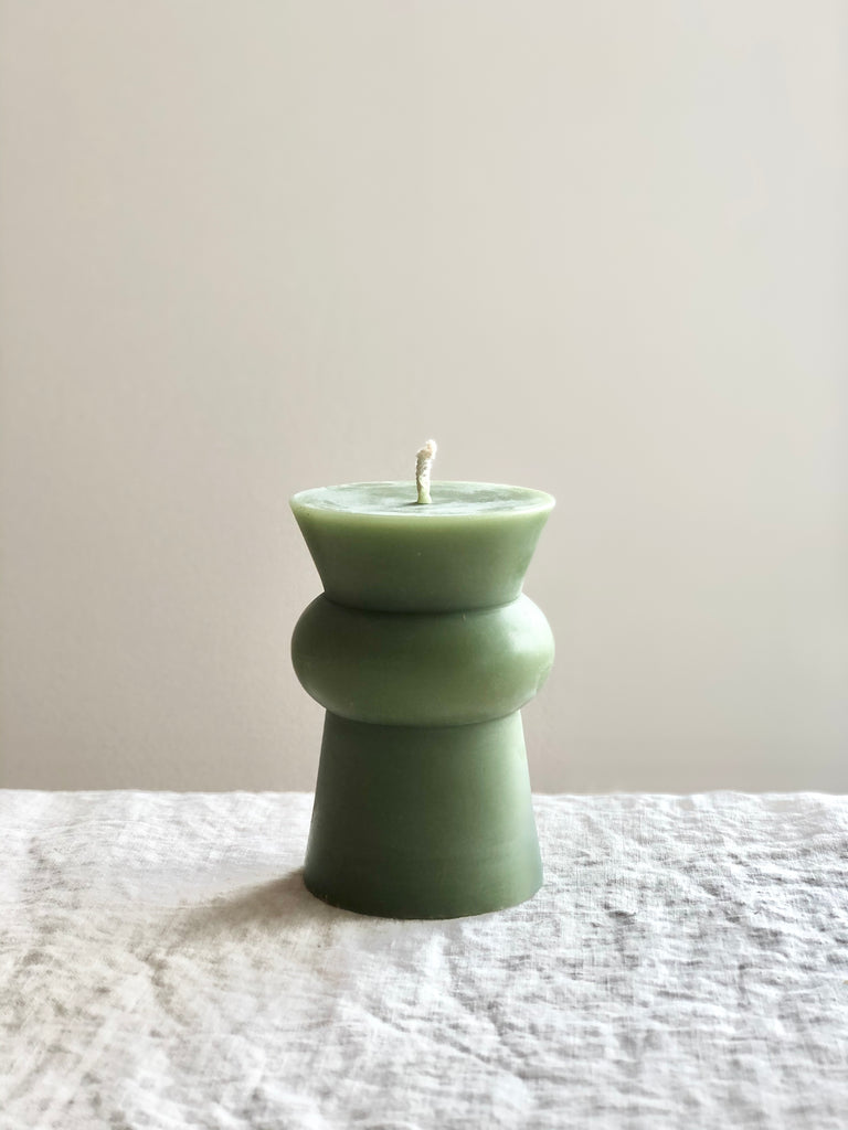 small light green totem candle on a table