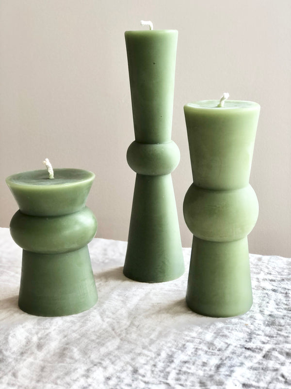 small medium and large light green totem candles on a white table