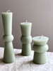 small green totem candle small medium and large on a table