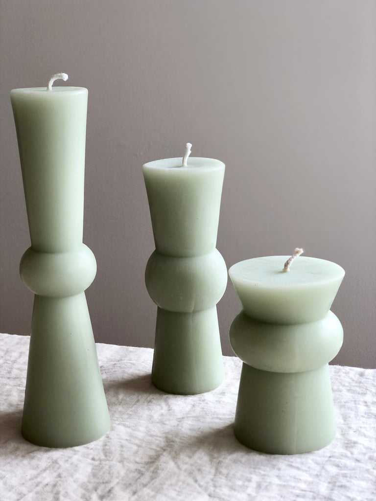 small green totem candle small medium and large on a table