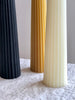 fluted black pillar candle made of beeswax on white table