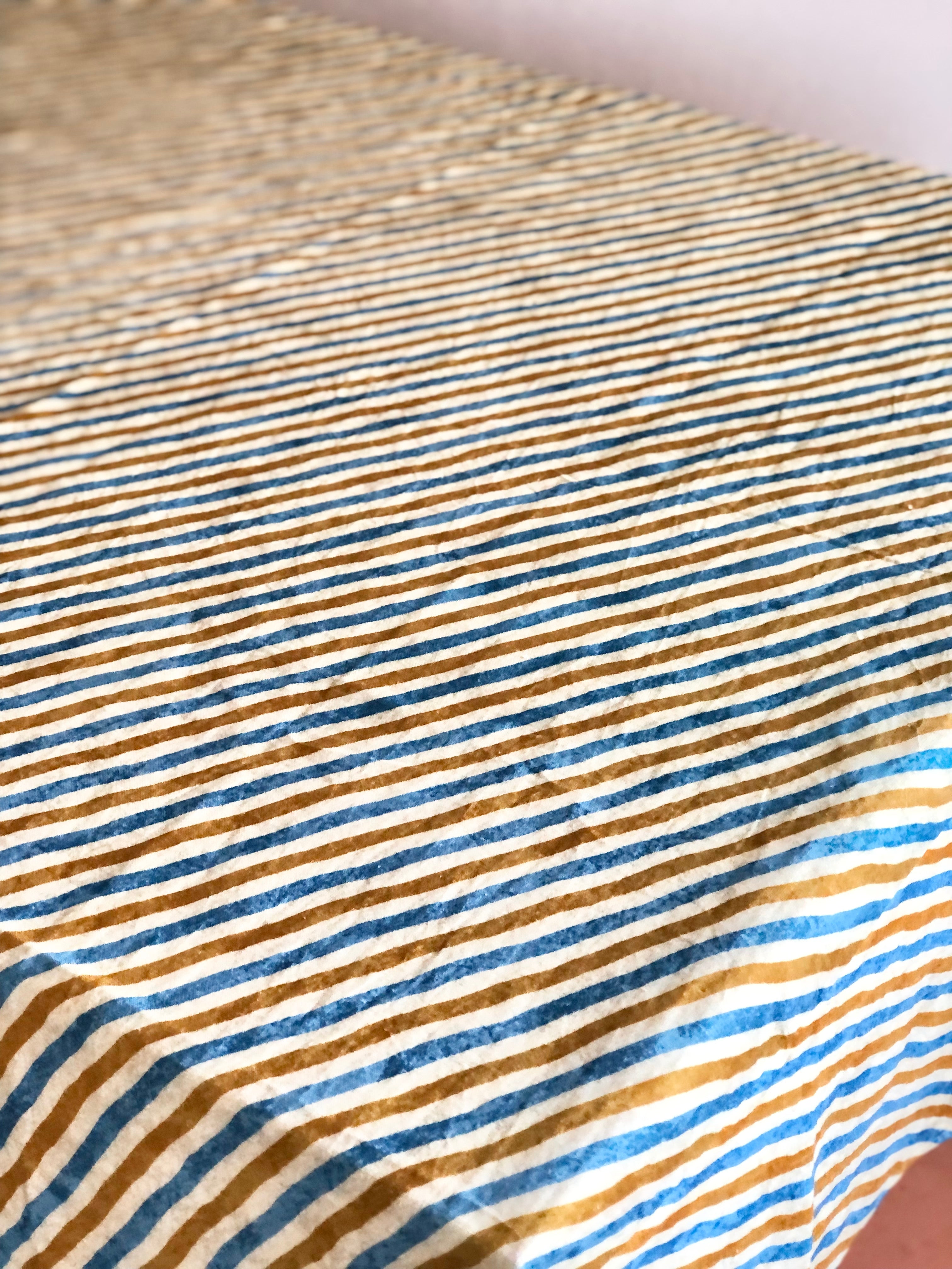 cotton tablecloths green with brown and blue stripes draped over a table top angle