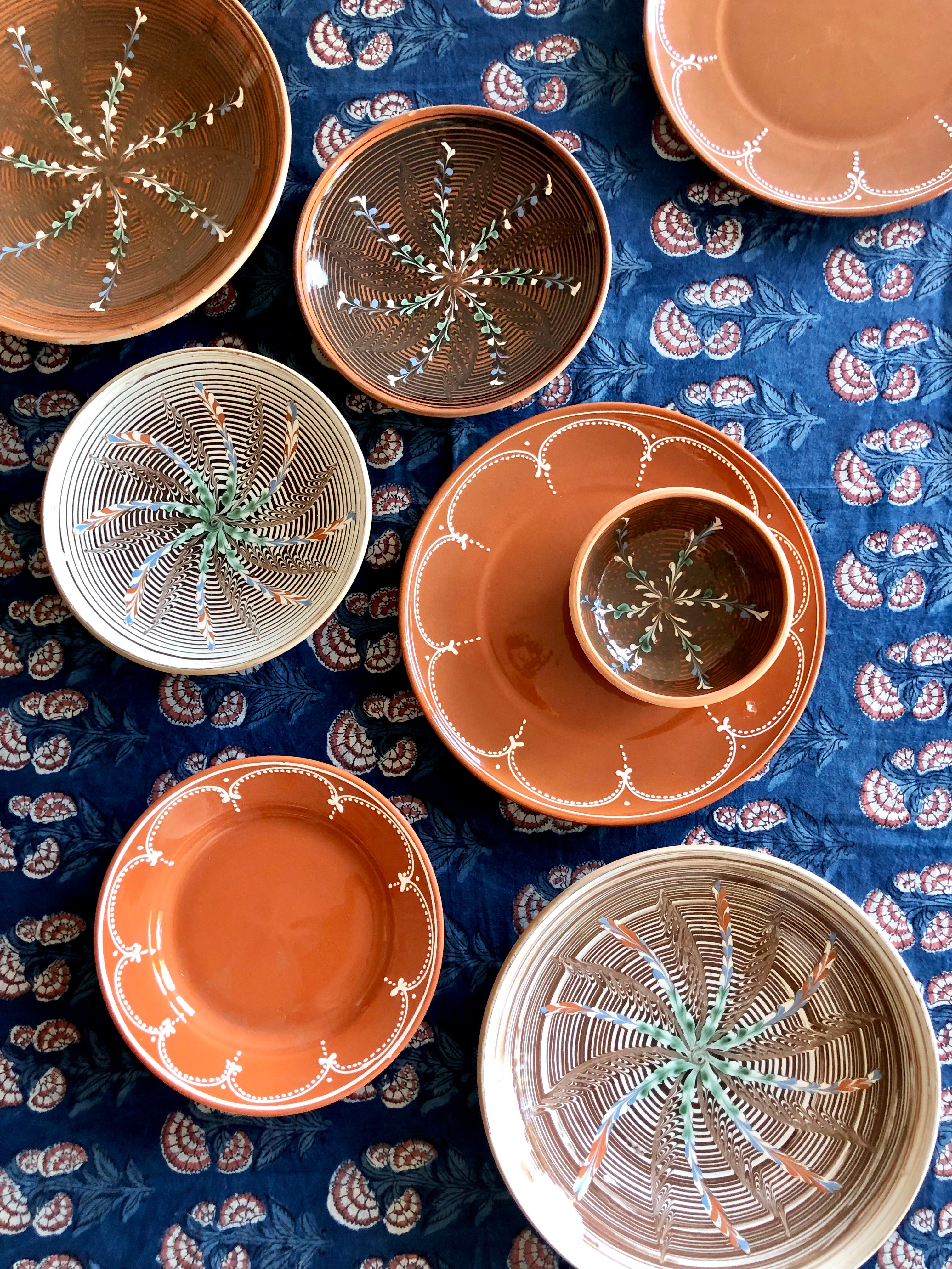 ceramic pasta bowl with radial leaf design in portocale color nested on blue tablecloth