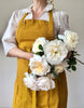 full length linen apron in mustard color worn by woman with peonies