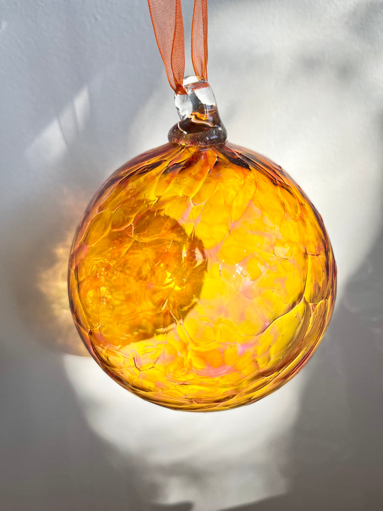 hand blown glass ornament with light and dark orange swirl pattern detail view
