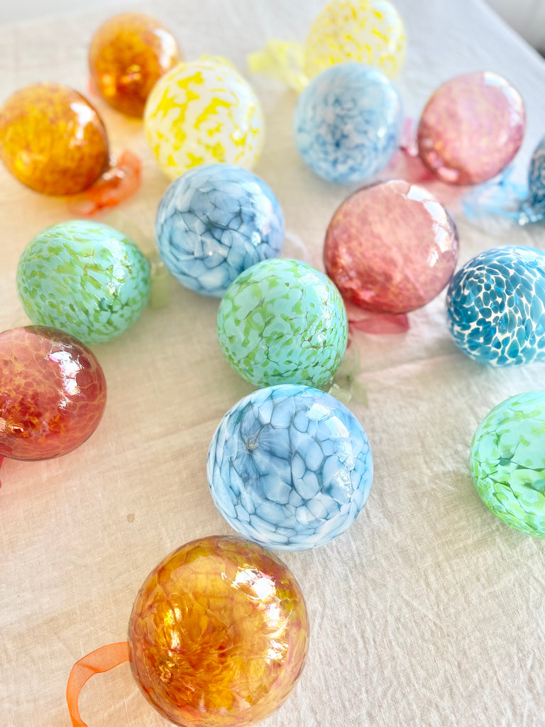 hand blown glass ornament with light and dark orange swirl pattern in group with other color options