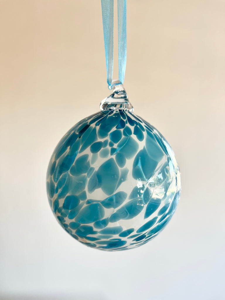 hand blown glass ornament with blue speckles hanging