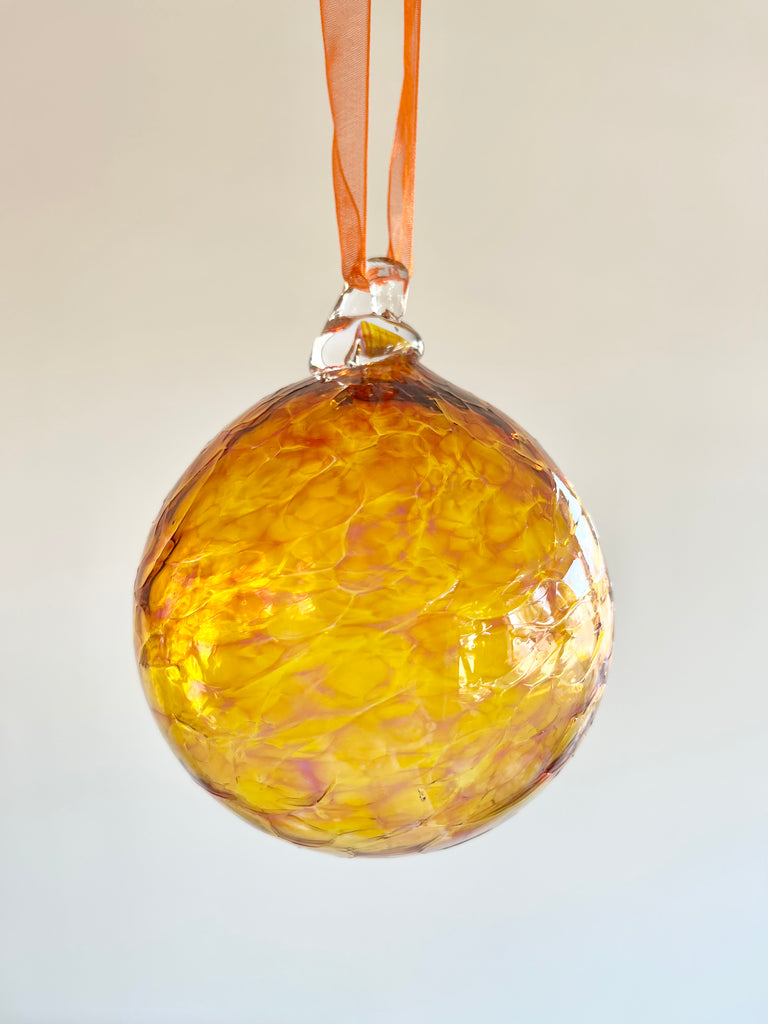 hand blown glass ornament with light and dark orange swirl pattern
