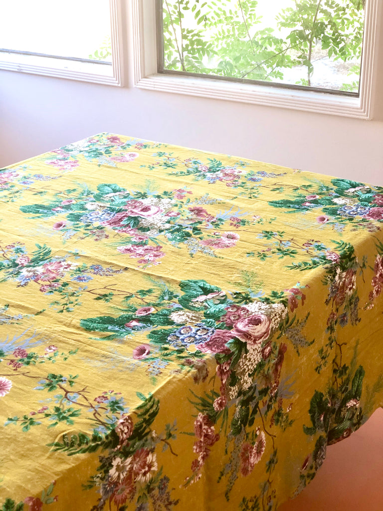 yellow tablecloth with pink white and blue floral pattern on table