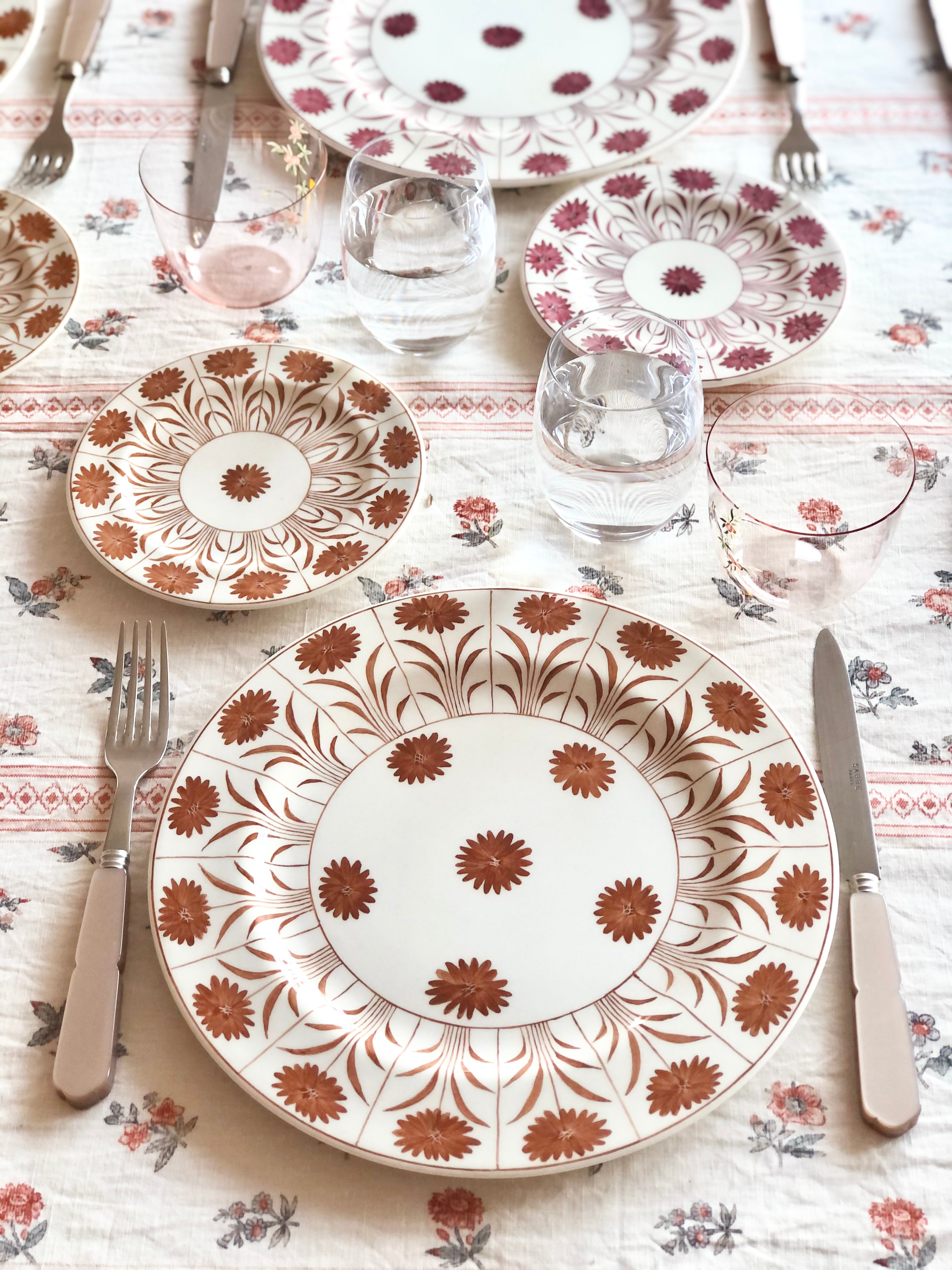 white tablecloth with red pinstripe and red floral pattern with placesetting