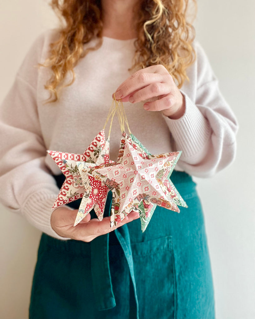 star shaped paper christmas ornaments in shades of green held by woman