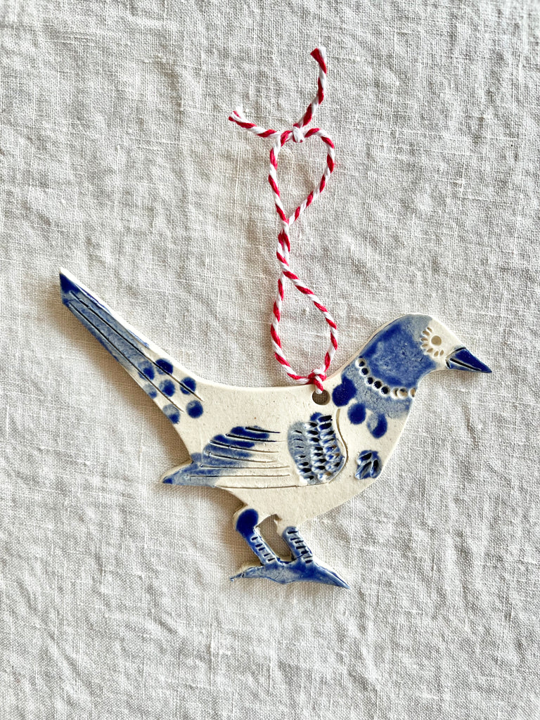 hand painted blue and white bird christmas ornament with red and white ribbon