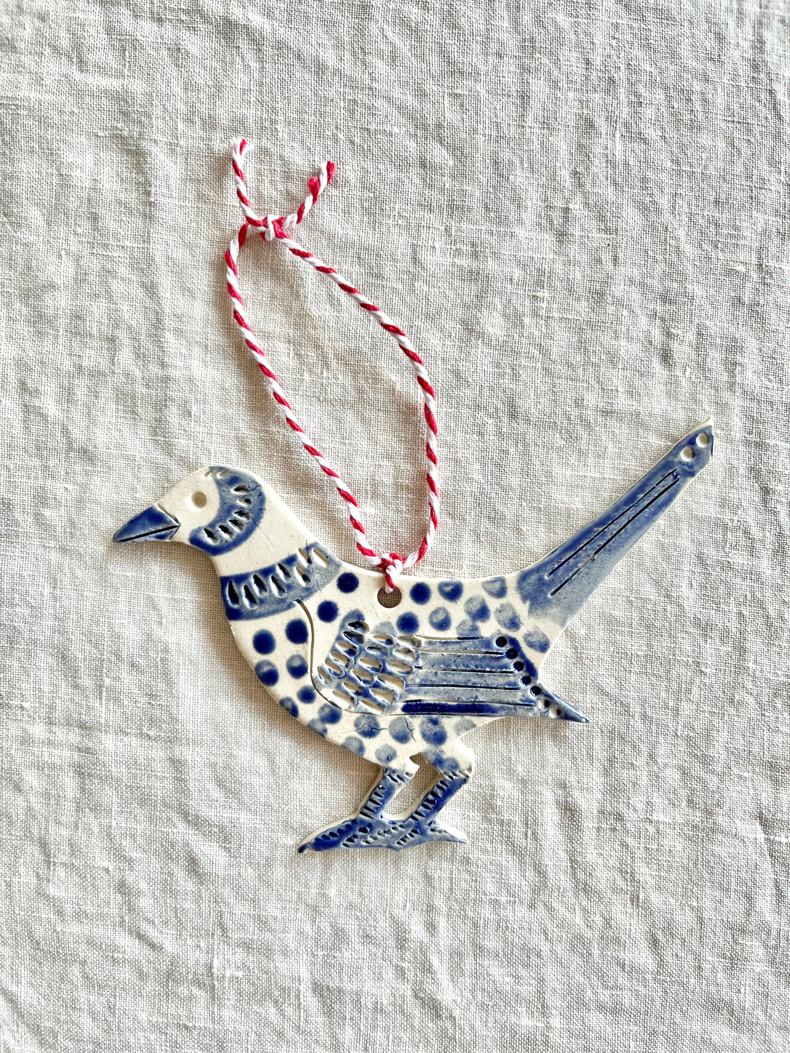 hand painted blue and white bird christmas ornament on linen tablecloth