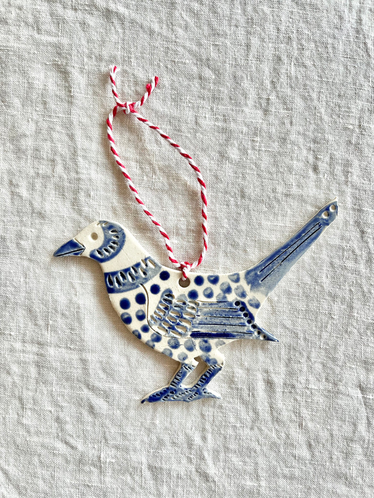 hand painted blue and white bird christmas ornament on linen tablecloth
