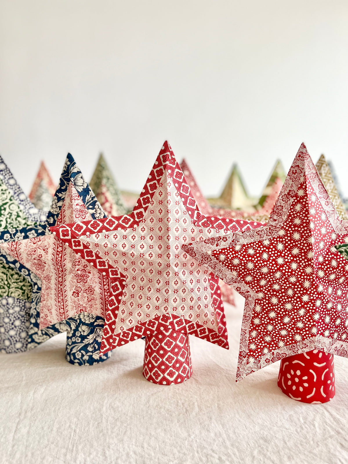 star tree topper with thin red and cream stripe pattern standing on table