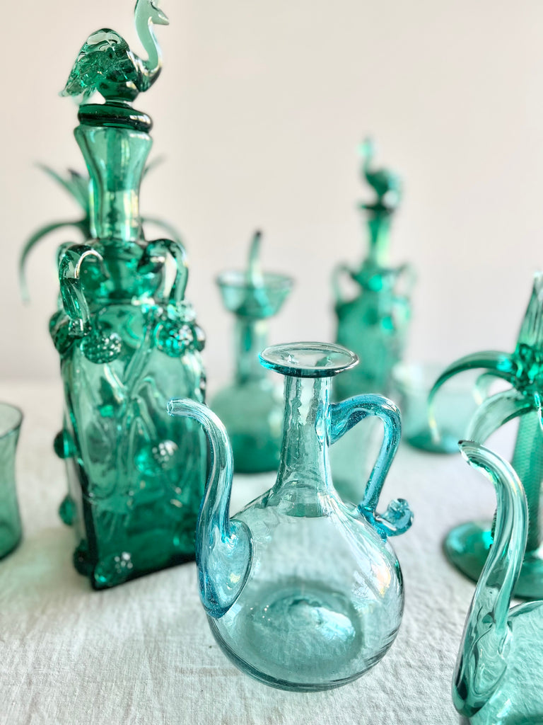 rectangular green glass bottle with stopper 15 inches tall on white table