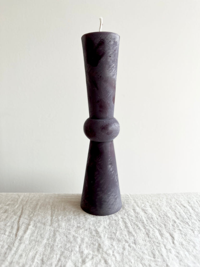 tall wine colored totem candle on white table cloth