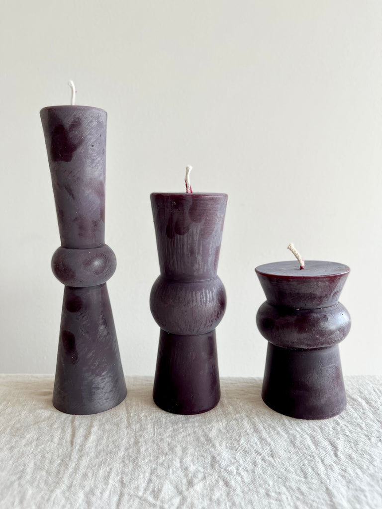 wine-colored totem candles small medium and large on a table