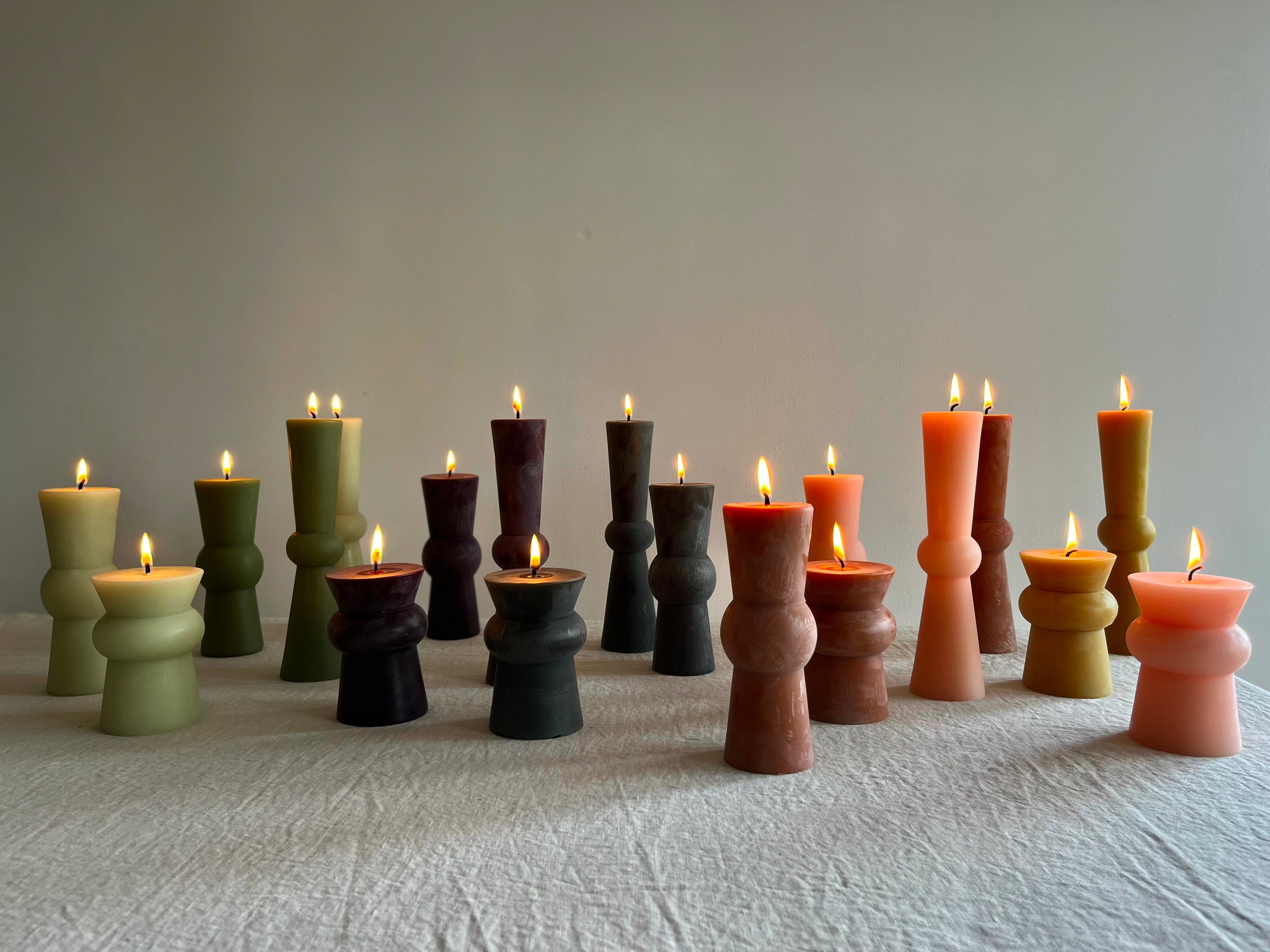 assorted totem candles on a table with flames lit.