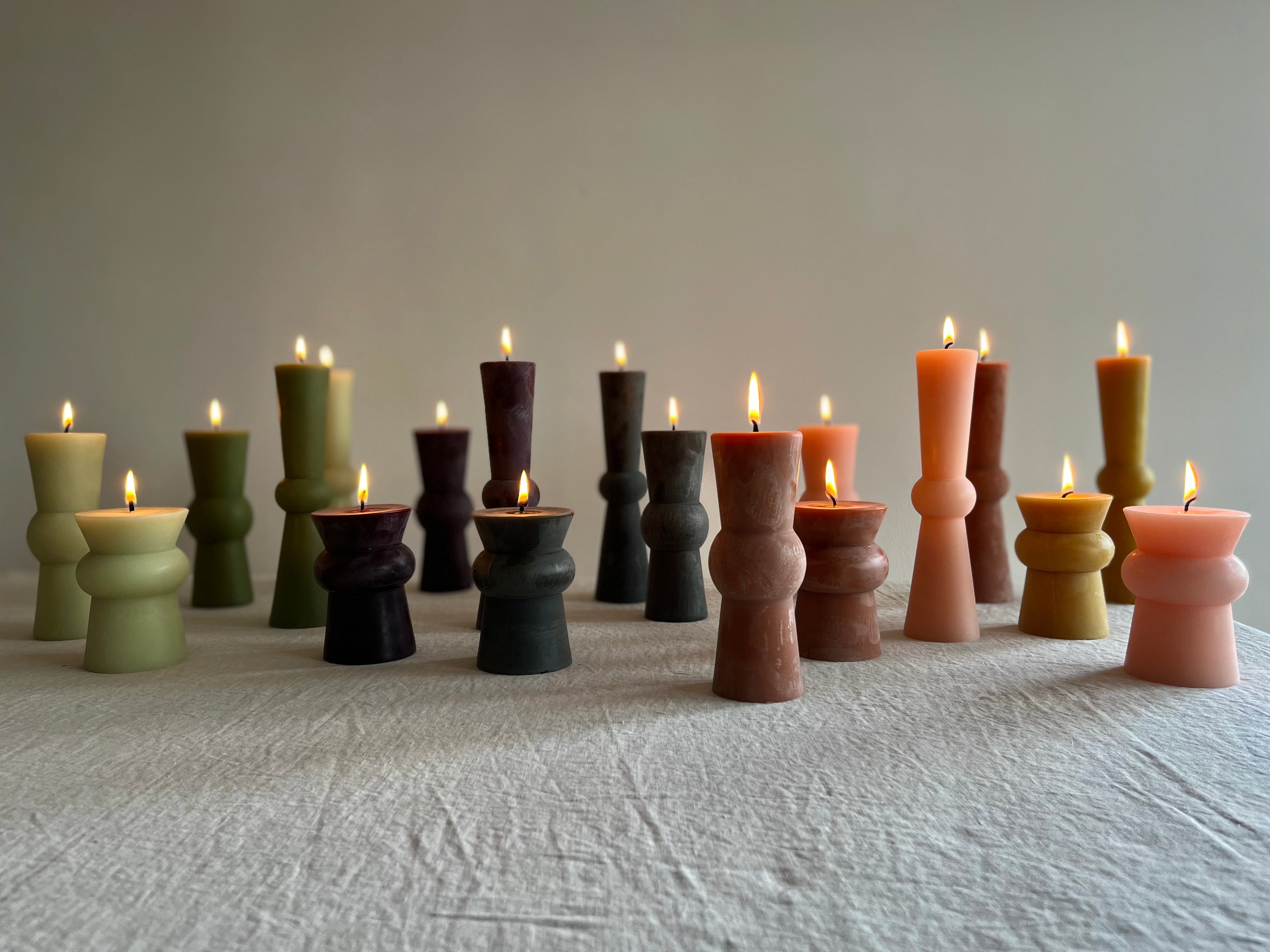 assorted totem candles green wine light pink on table with flame