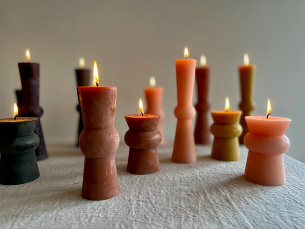 small wine colored totem candles with light pink and terra colors and flame lit