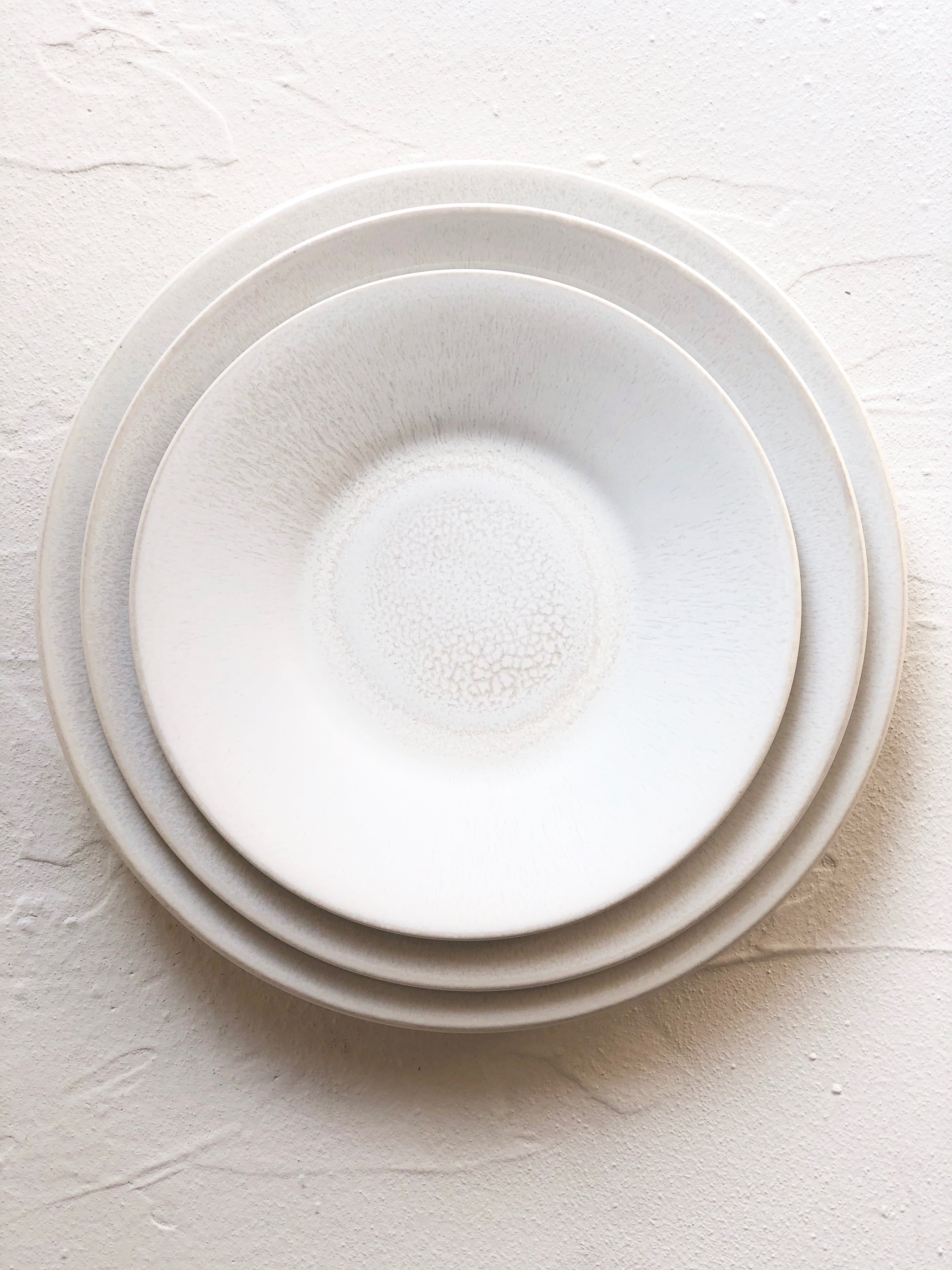 charger plate with white on white reactive glaze 11.5 inches diameter stacked with dinner and salad plate