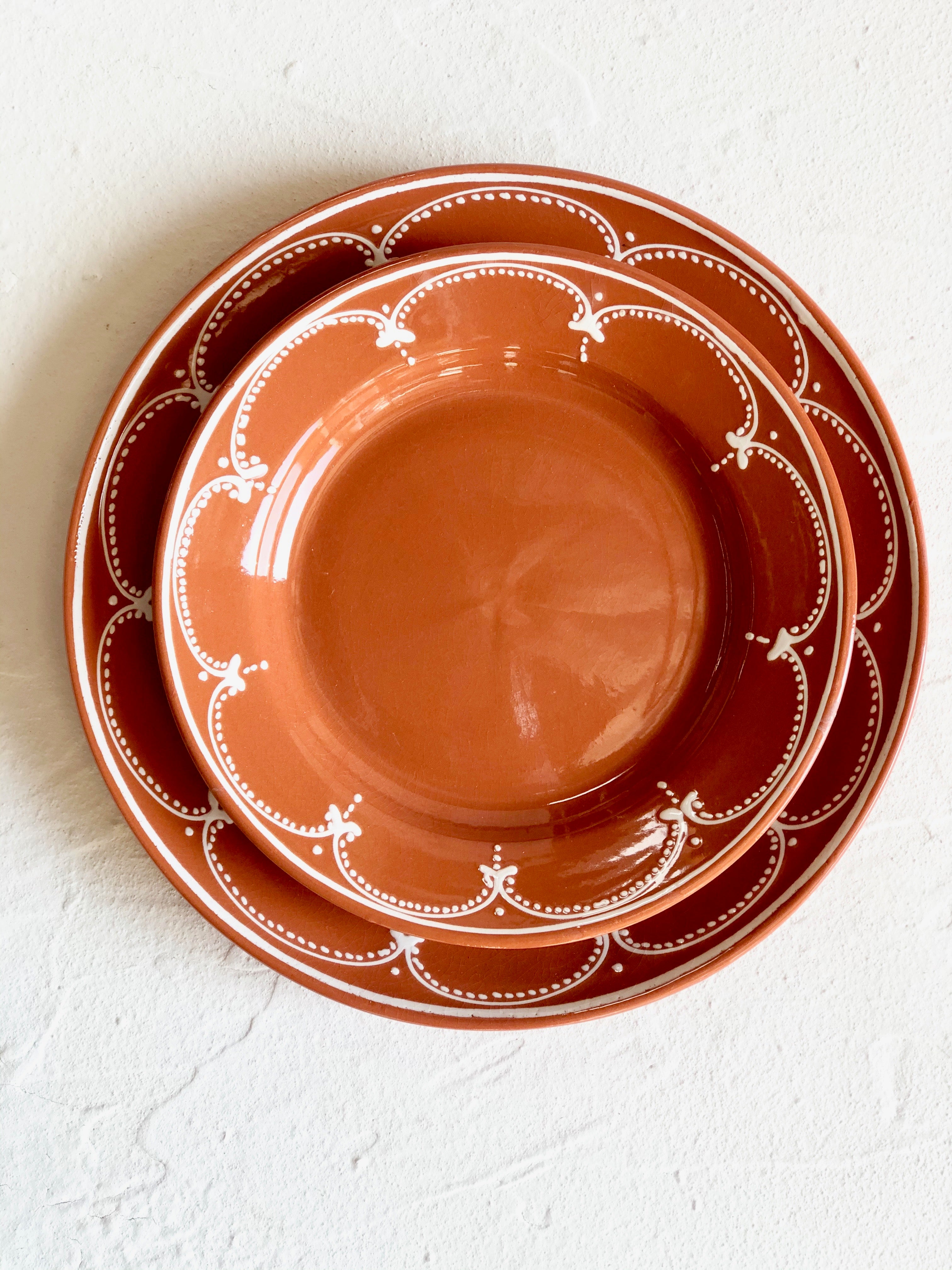 brown salad plate with white scallop design on rim with dinner plate