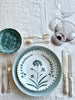 green bread plate with hand painted white floral design on white linen